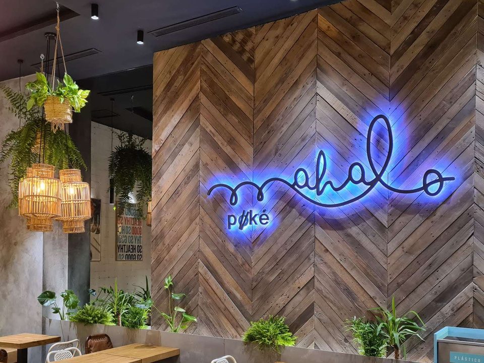 Pared con el neón de Mahalo Poke en uno de sus locales